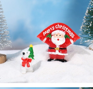 Close-up of Santa Claus holding a Merry Christmas banner and a polar bear holiday ornament