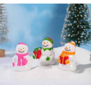 Detalle de tres muñecos de nieve en miniatura de resina con bufandas de colores en nieve