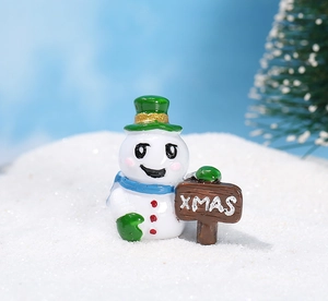 Detalle macro de una figura de muñeco de nieve de resina con cartel XMAS sobre nieve