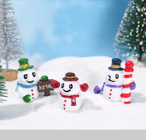 Detalle de tres muñecos de nieve de resina en un micro paisaje para decoración navideña