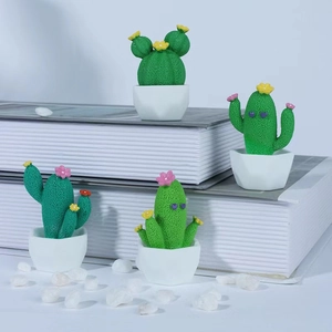 Set of four cute miniature resin cactus plants with colorful flowers on white books