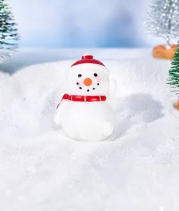Figura miniatura de muñeco de nieve navideño con gorro rojo y bufanda sobre fondo nevado
