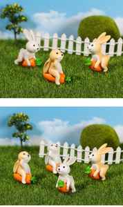 Detailed view of miniature resin bunnies with orange carrots in a fairy garden landscape