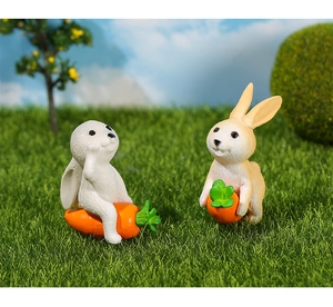 Detailed view of two cute resin rabbits with carrots on green grass for micro landscapes