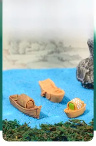 Vista dettagliata di tre barche in miniatura in resina su sabbia blu con piante