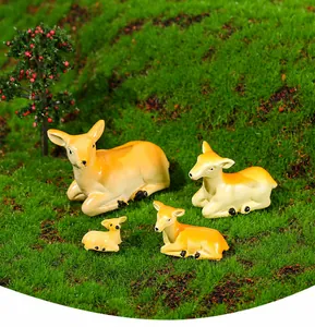 Detailed macro view of a four-piece resin deer family set on green moss garden decor