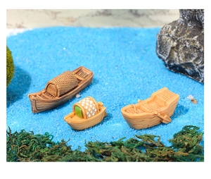 Modelli di barche in miniatura in resina su sabbia blu con muschio per micro paesaggi