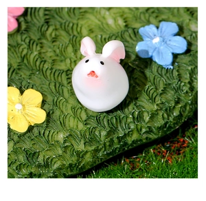 Vista macro di una statuetta di coniglio bianco in miniatura su muschio con piccoli fiori colorati