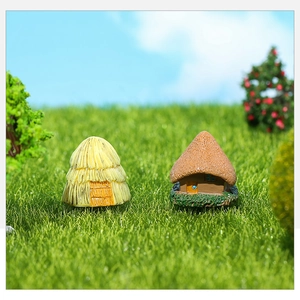 Detailed view of two miniature resin thatch cottages on mossy green miniature garden decor