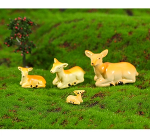 Detailed view of four miniature resin deer figurines on a lush artificial grass lawn