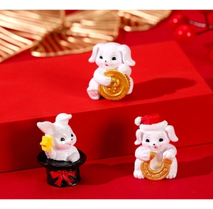 Three cute miniature resin rabbit figurines with gold festive icons on red display stand
