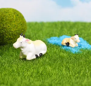 Dettaglio di due statuette di mucca in miniatura in resina per decorazioni micro paesaggio