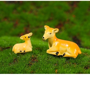 Close-up of cute resin deer miniatures on green moss for micro landscape garden decor