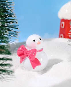 Vista macro de un muñeco de nieve de resina en miniatura con lazo rosa en escena de nieve