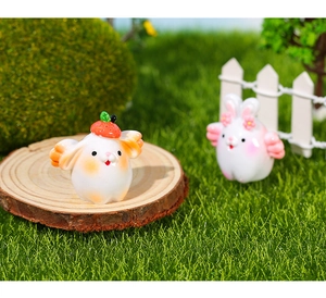 Detail of miniature resin rabbit figurines with strawberry and pink flower decorations