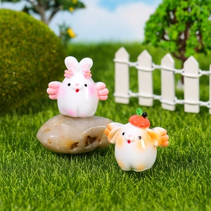 Miniature flying bunny figurine with strawberry hat in a fairy garden landscape