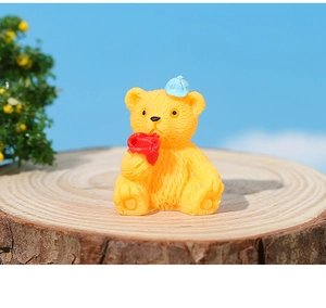 Makroaufnahme eines gelben Harz-Teddybären mit roter Rose für DIY Miniatur-Landschaften