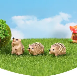 Vue macro de trois hérissons miniatures en résine sur gazon pour micro-paysages