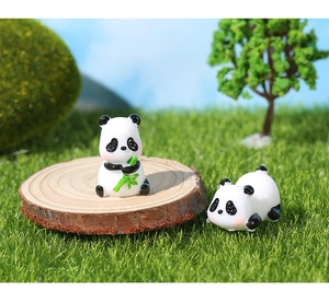 Miniature resin pandas on a wood slice with a bamboo shoot for garden decor