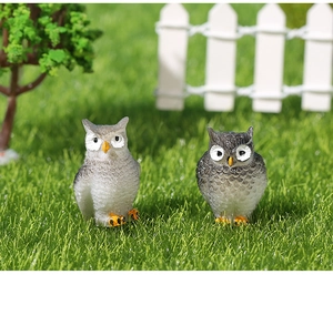 Miniature di gufi in resina in tonalità di grigio poste in un micro paesaggio fatato