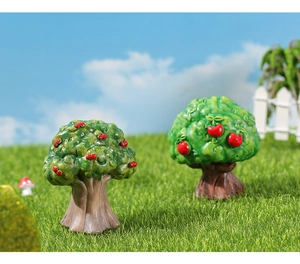Detailed macro view of two miniature resin fruit trees with bright red fruits on grass