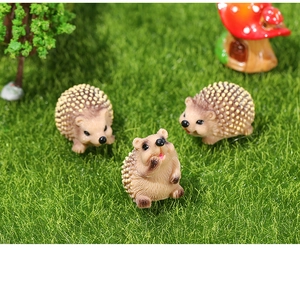 Macro de trois figurines de hérissons en résine sur l'herbe avec petite maison champignon