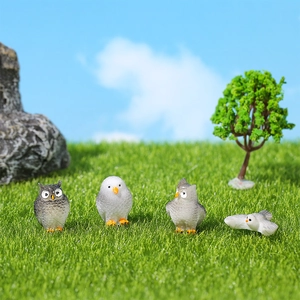 Statuine di gufo in miniatura per micro paesaggi su sfondo di prato verde lussureggiante