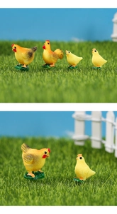 Close-up of miniature resin chicken family models on a farm scene with green grass