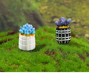 Macro shot of miniature cactus resin plants in checkered pots on green moss