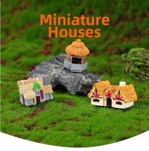 Detalle de casitas en miniatura de resina sobre musgo para decoración de micropaisajes