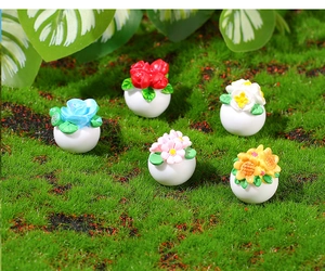 Close-up of five miniature resin dollhouse flower pots on a mossy green background