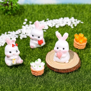 Miniature resin rabbit figurines set with carrot baskets on green grass scenery