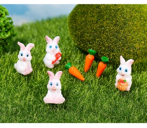 Miniature resin white rabbits and carrots set displayed on green moss and artificial grass