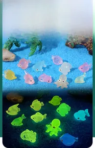 Luminous miniature sea animal figurines showing glow-in-the-dark effect in blue aquarium sand