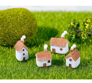 Detalle de casas en miniatura de resina sobre césped de musgo para micro paisajismo