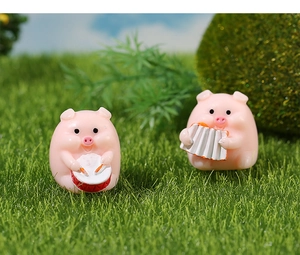 Detailed view of cute pink resin pigs playing drums and accordion on green grass