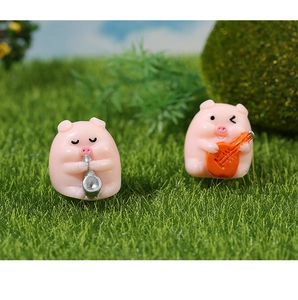 Close-up of cute resin pigs playing saxophone and guitar in a green micro landscape