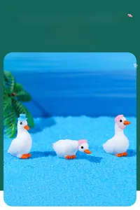 Miniature resin white swans with blue hats and pink scarves on a beach setting