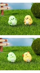 Close-up of cute green and yellow resin dragon figurines in a micro landscape garden