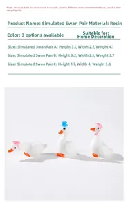 Detailed macro view showing three white resin swan miniatures with pink and blue hats