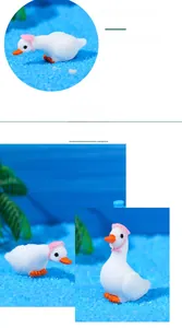 Close-up of miniature white resin swans with pink sun hats in creative micro landscape décor