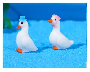 Detail of miniature resin swans featuring blue gentleman hat and pink sun hat decor
