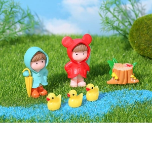 Miniature garden figurines set with kids in raincoats, ducks, and stump on moss