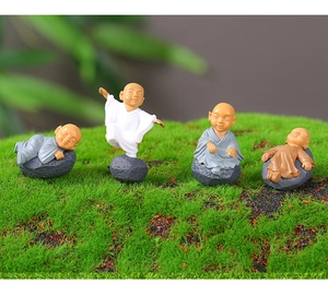 Detailed macro view of four miniature resin monk figurines on mossy garden background