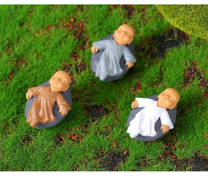 Detailed view of three sleeping monk figurines on moss base for micro landscapes