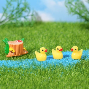 Miniature yellow duck figurine set for garden decor with tree stump on blue sand