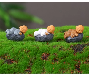 Three cute miniature monk figurines sleeping on stones for Zen micro landscape decoration