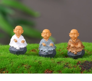 Detailed view of three resin monks in white, gray and brown robes on stone bases