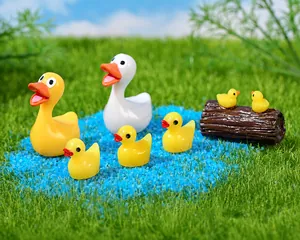 Miniatuur eenden van hars in een gesimuleerde tuinvijver met blauw zand en kunstgras decor