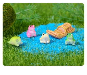 Miniatuur kikkerfiguren en een kleine houten boot op kunstgras vijverscène